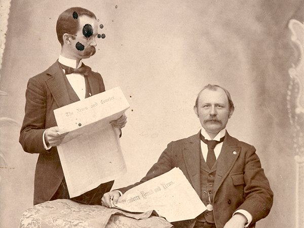 Old photo of two men holding newspapers