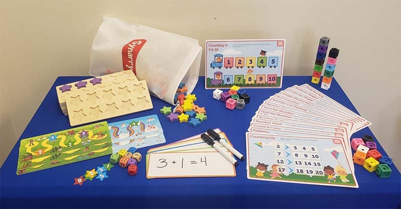 The School Readiness: Preschool Math kit spread out on a blue table featuring math concept games, cards, and cubes.