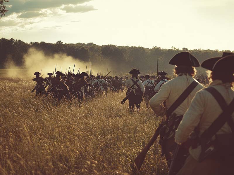 Colonial militia reenactors in a field.