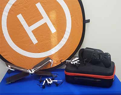 A drone on a blue draped table with a round landing pad with a big H behind it.