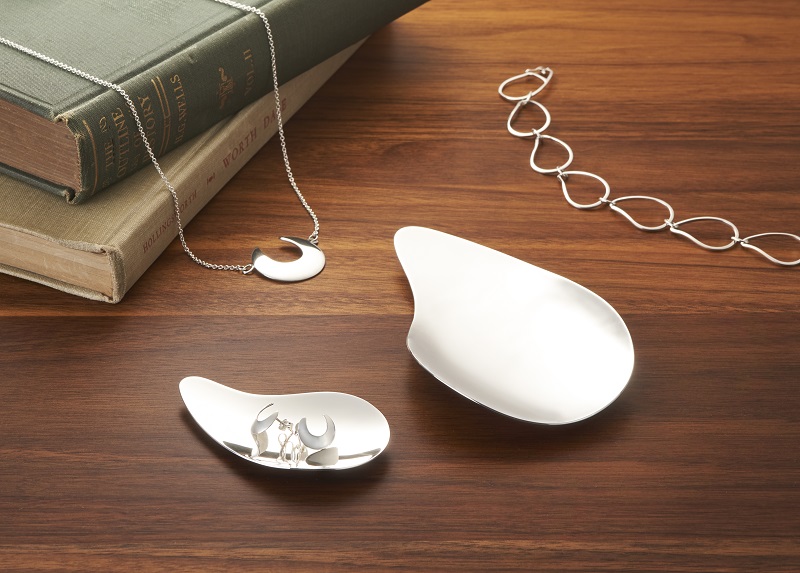 Silver oyster shaped jewelrey on a wooden table.