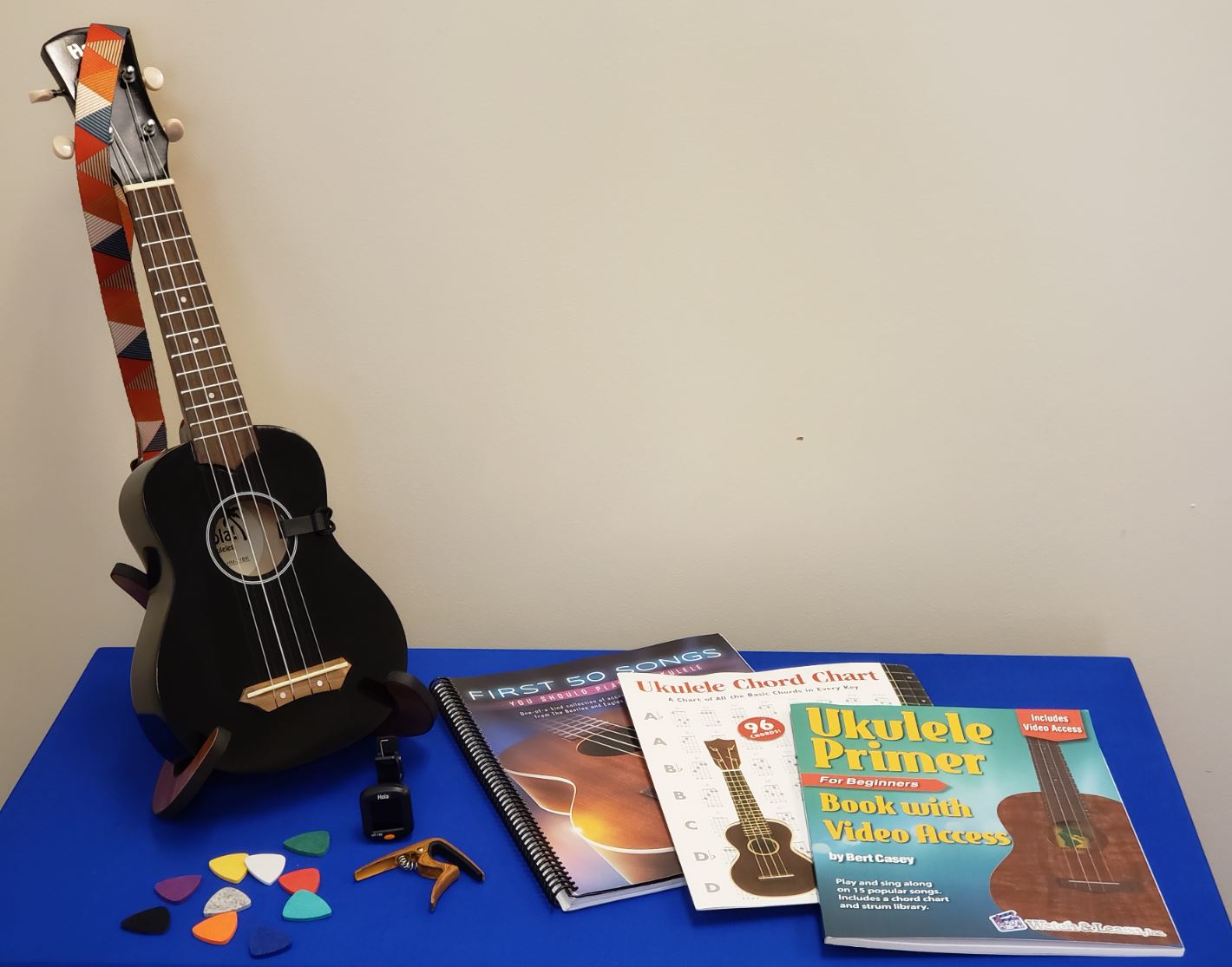A ukulele and music books sit on a blue table. 