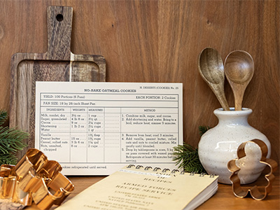 Recipe card, cutting board, and utensils on a table in preparation for cooking.