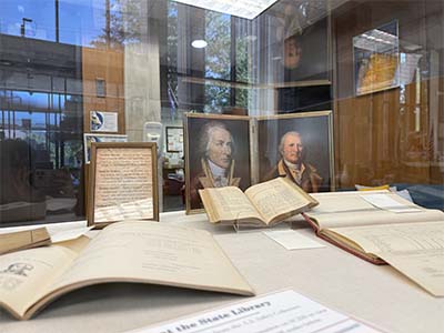 Items in the display case in our library lobby featuring books and paintings of the Revolutionary War.