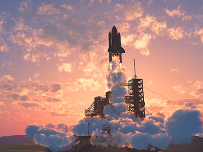 The space shuttle taking off early morning in front of a sunrise.