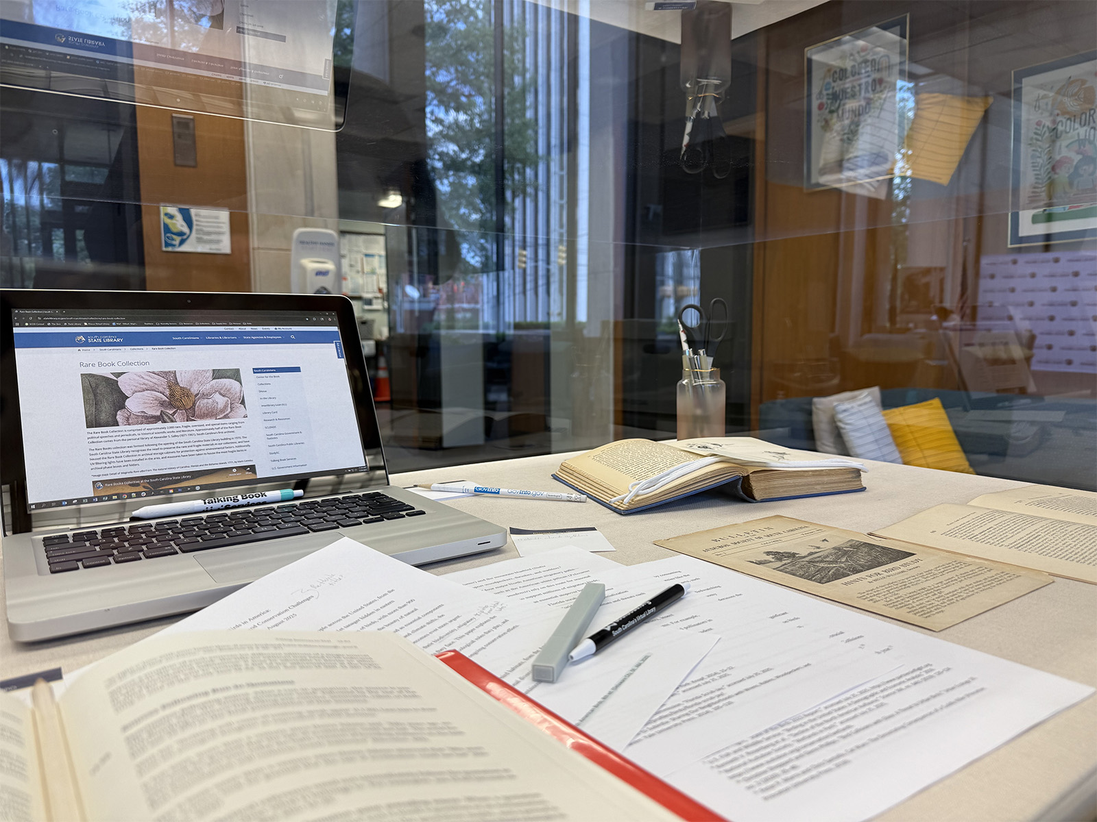 Items in the display case featuring books from the Rare Book collection and a laptop opened to the rare Book page on the website.