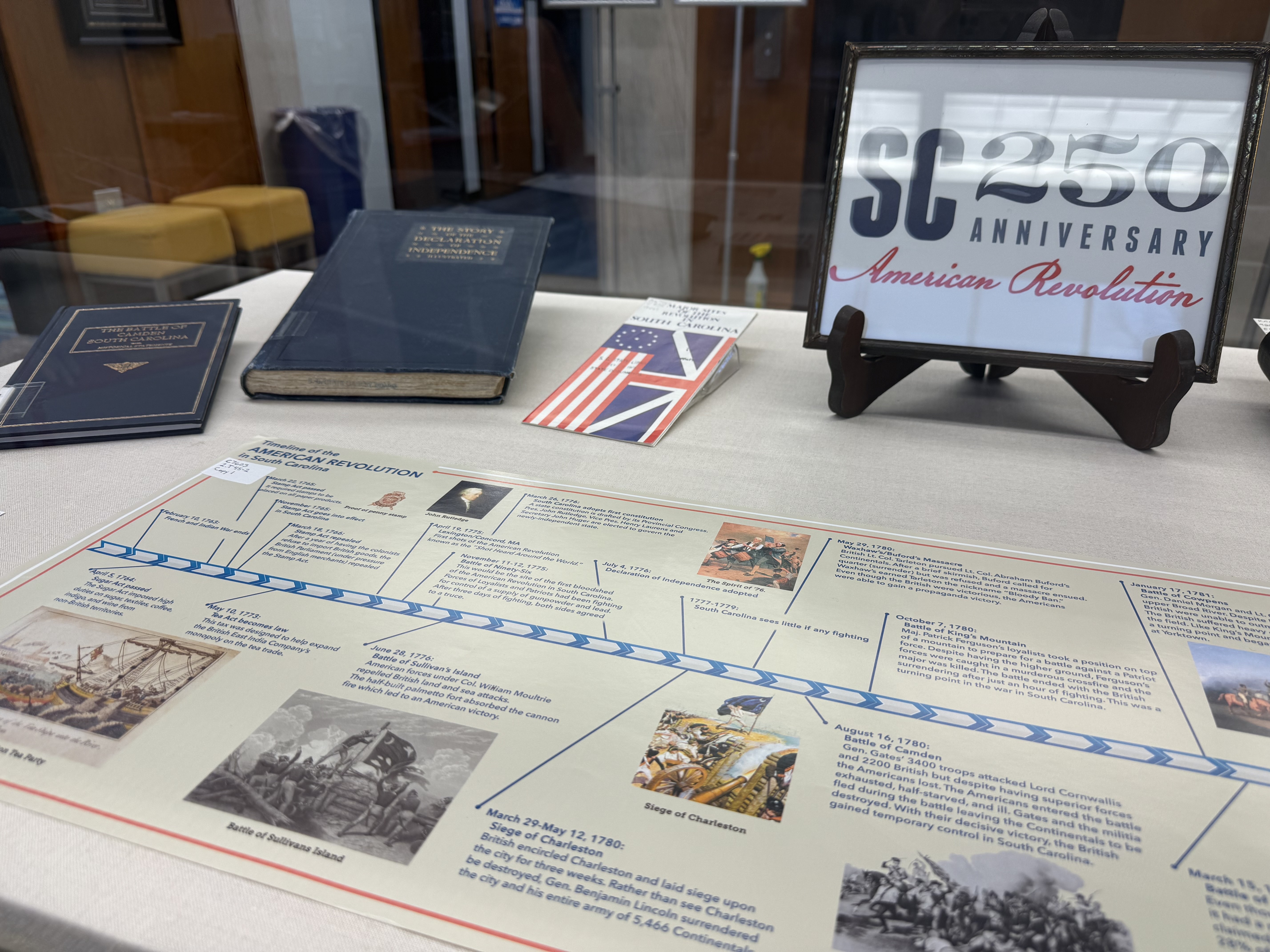 The SC 250 logo in a picture frame and a timeline of the Revolutionary War in our lobby display case.