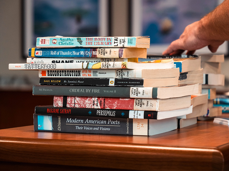 A stack of books on a table waiting to be shelved.