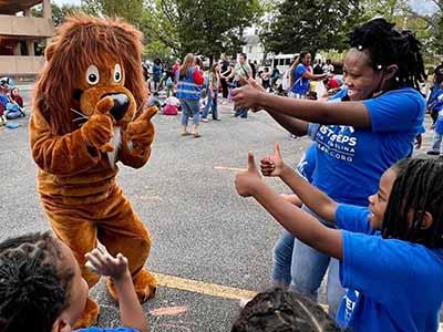 Dewey the Lion mascot interacts with Read-In students.