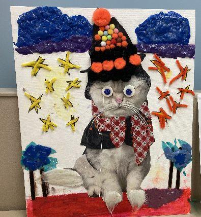 A tactile cat made of cotton, googly eyes, and pom poms. 