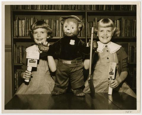 A black and white photo of two young girls with a Smokey Bear doll