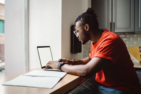 An African American man working on a laptop computer. 