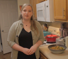 Lyndsey Maloney standing in her kitchen. There is a bowl of Lo Mein sitting on the counter beside her. 